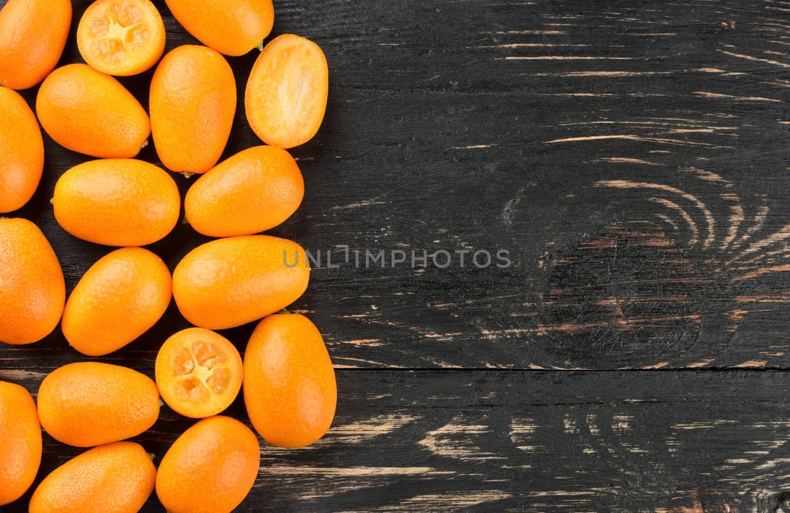 Fresh fruit kumquat on an empty wooden background, top view