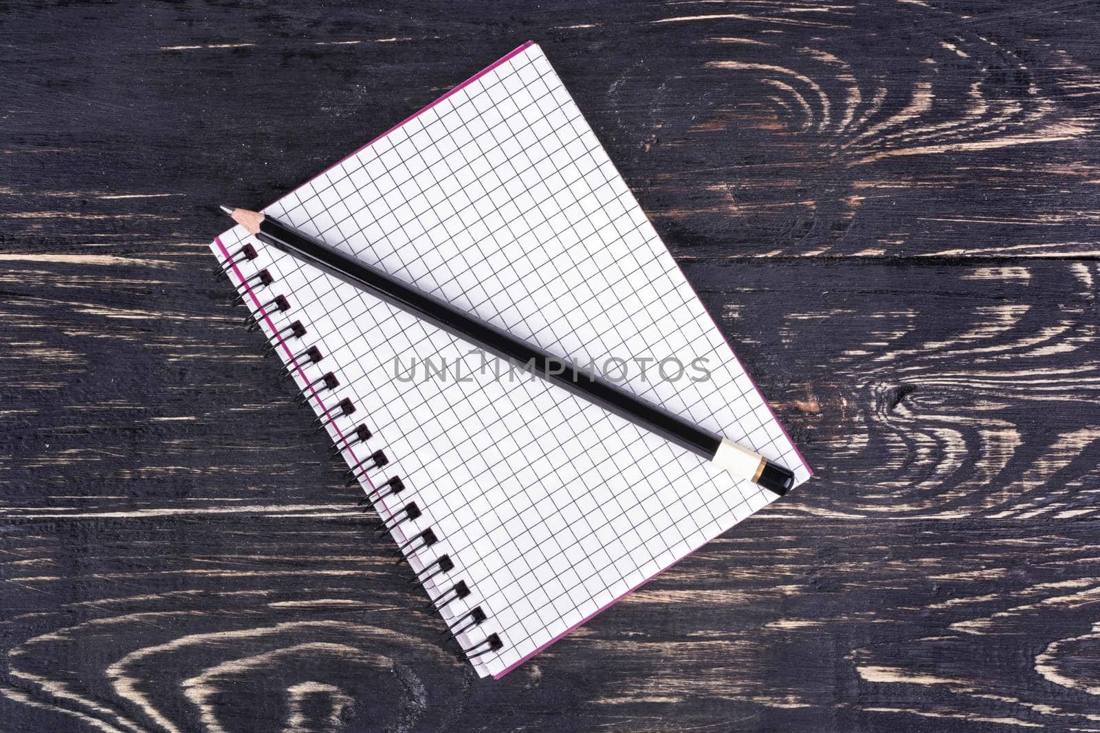 Open blank notebook with a pencil on a dark wooden background