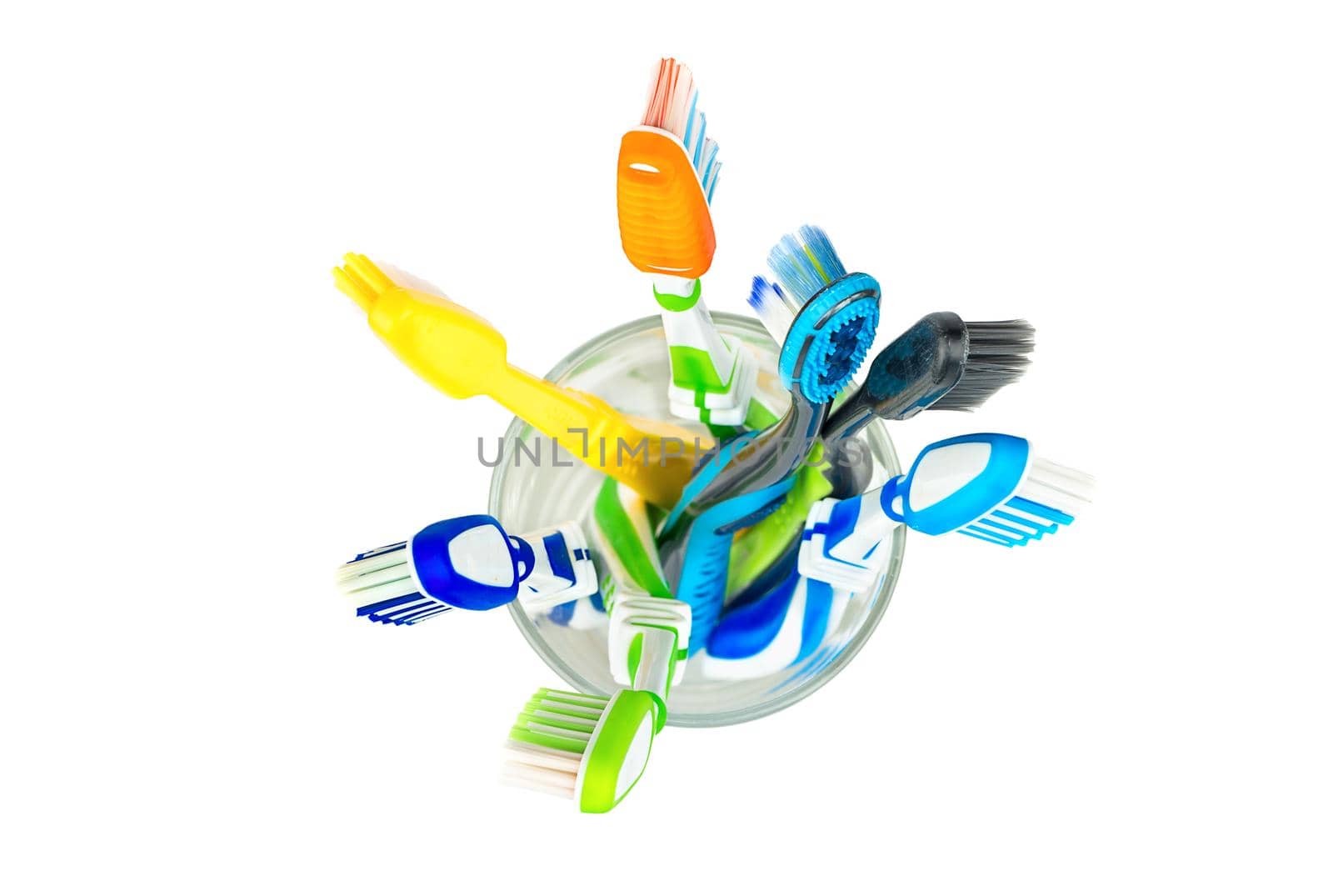 Many toothbrushes in a glass on a white background, top view