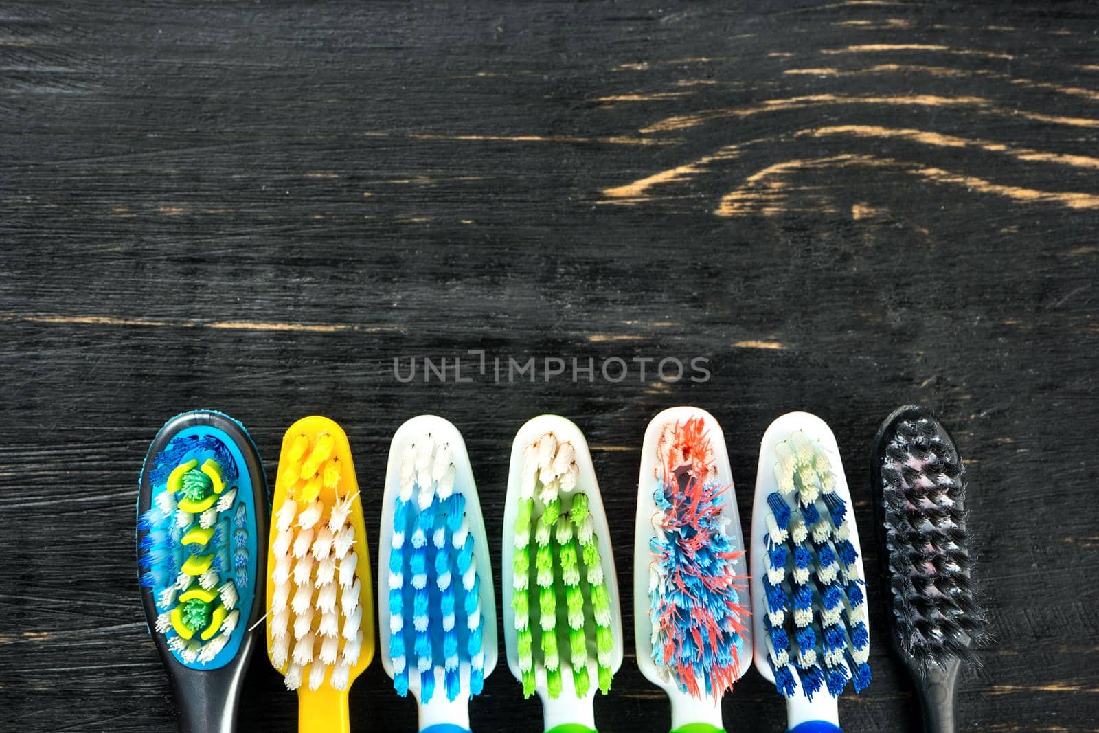 Multicolored toothbrushes on a wooden background close up