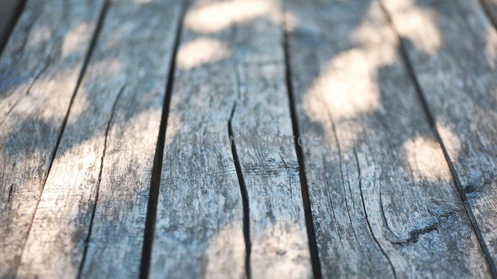 An old wooden table in a summer garden with rays of sunshine