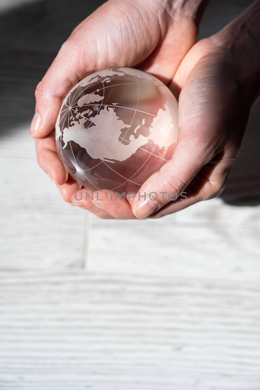 Close-up of female hands with a crystal globe on a woody background