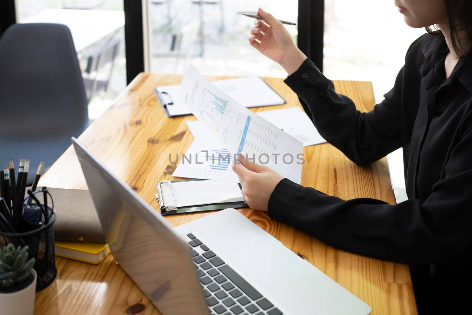Businesswoman sitting in front of laptop and checking financial reports.