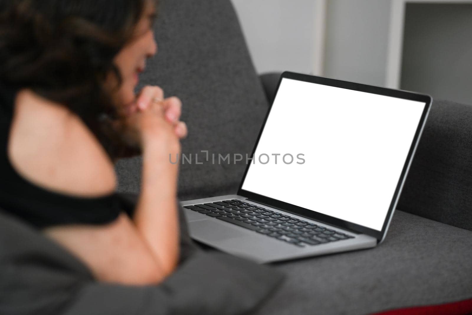 Relaxed mature woman lying on couch and watching movie in laptop computer.