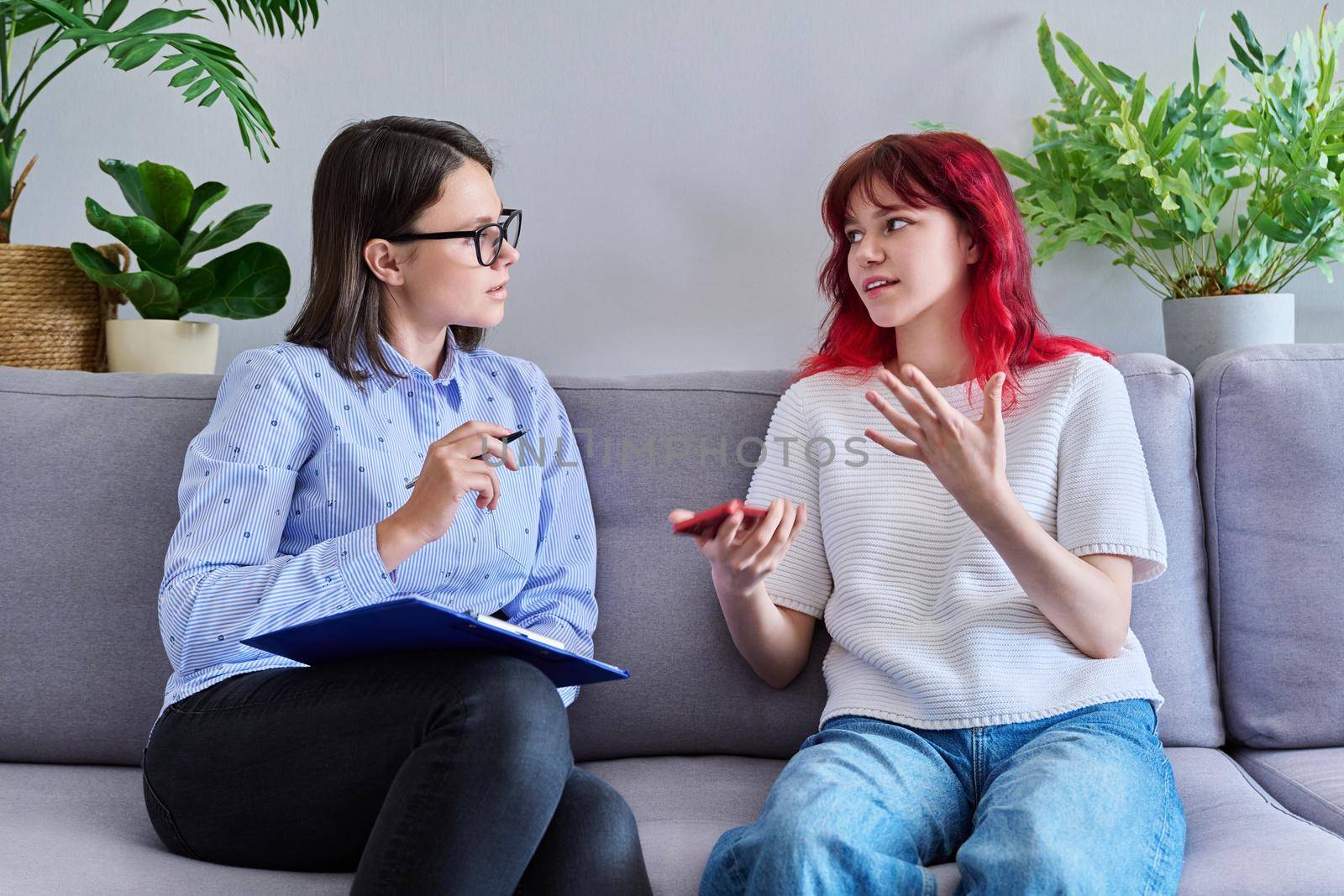 Psychologist counseling teenage female, individual therapy in doctors office. Professional counselor helping teenager, girl with smartphone. Mental health, adolescence, psychology, psychiatry concept