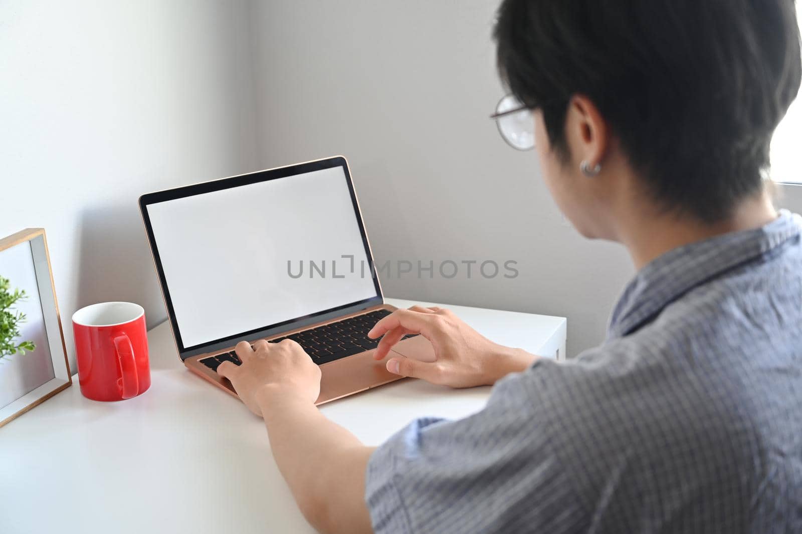 Rear view asian man browsing internet with laptop computer at home.