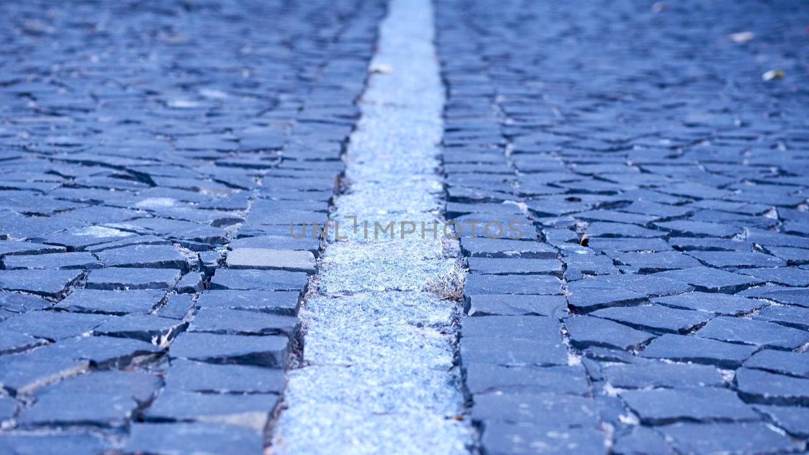 of a piece of ground, covered with concrete, asphalt, stones, or bricks.Paving stones. Cobblestone pavement divided by a granite strip close-up.