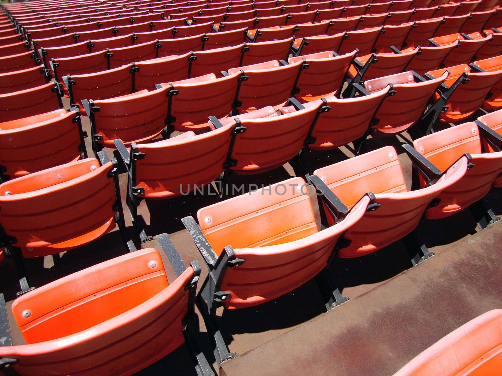 Rows of empty orange stadium seats by EricGBVD