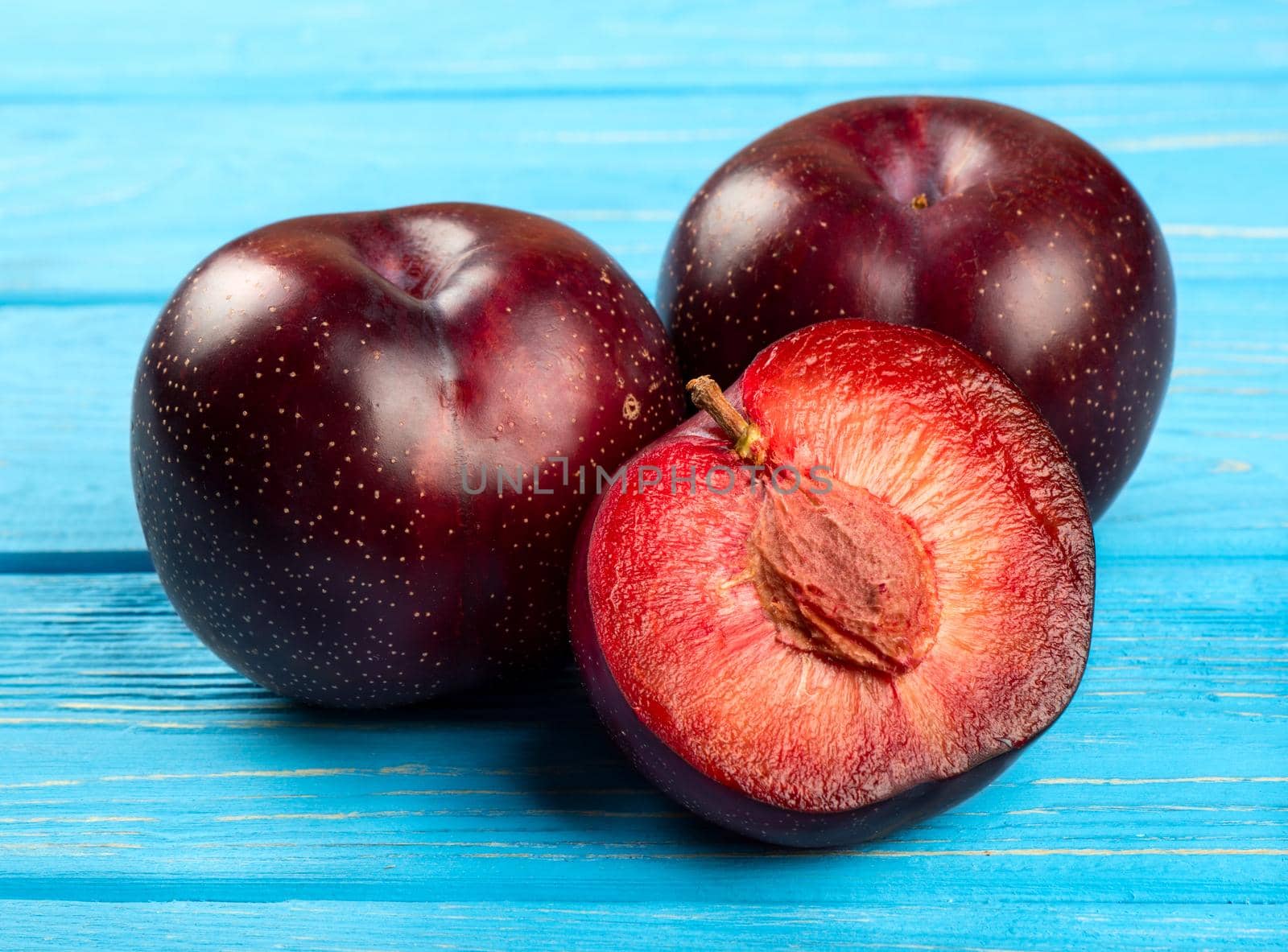 Fresh large red plum with a mate on wooden background