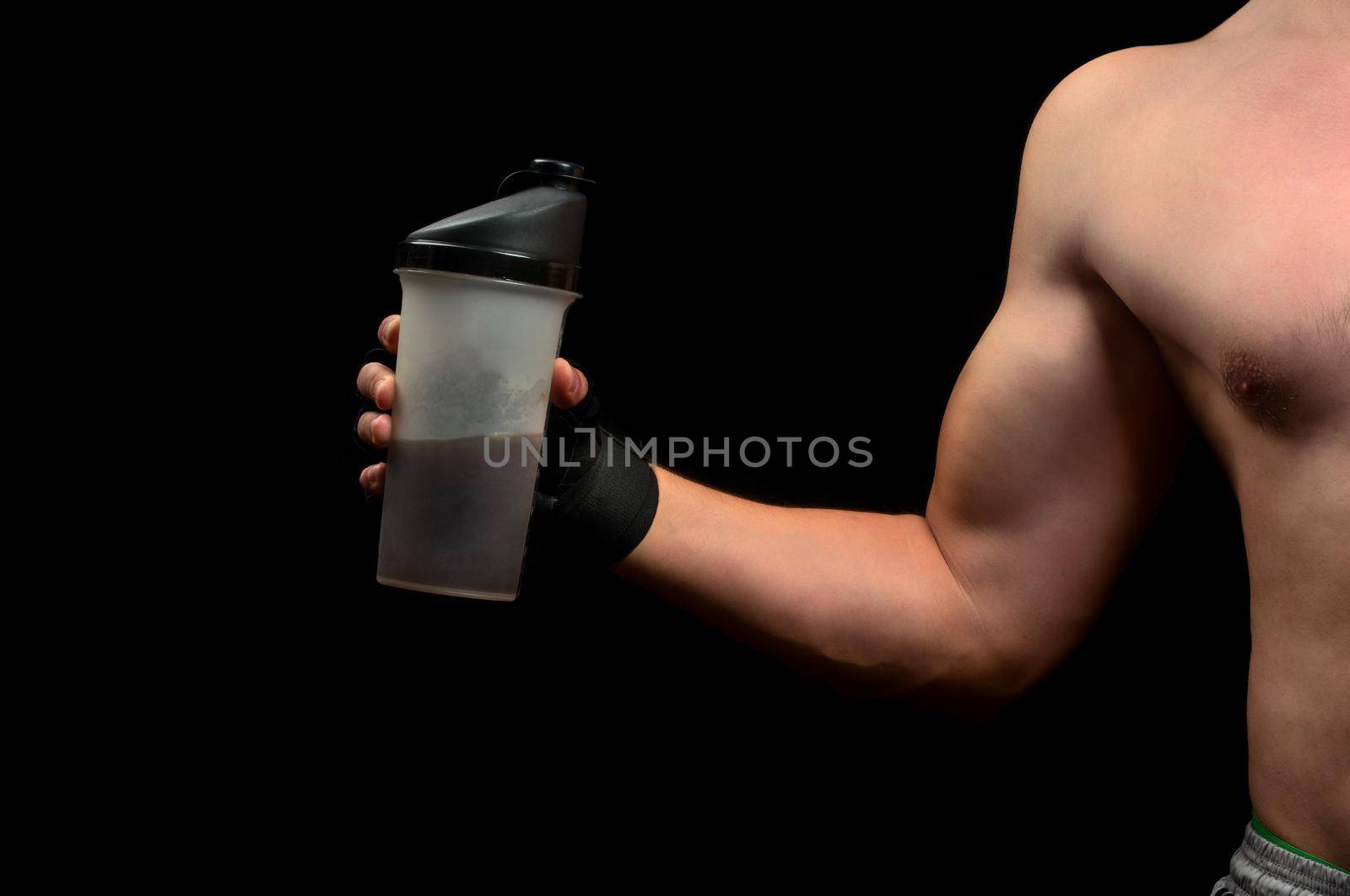 Beginner bodybuilder is holding a sports nutrition on a black background