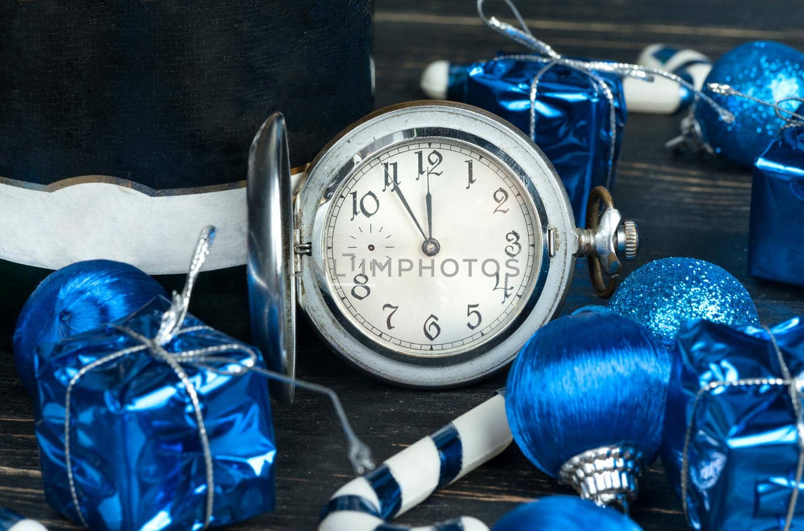 Christmas balls, decorations, bottle of champagne and watch on wooden background