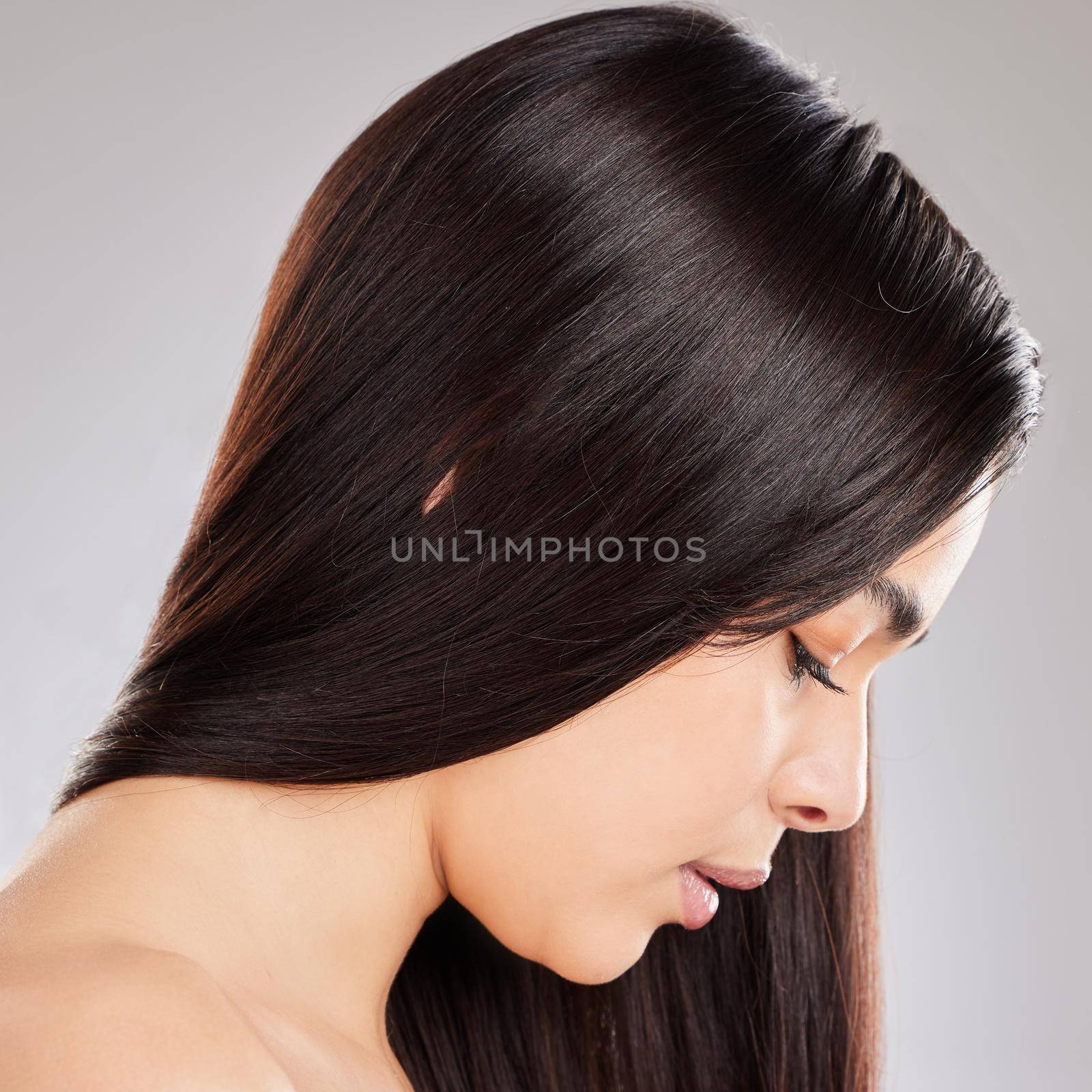 Studio shot of a woman with beautiful brown hair posing against a grey background.