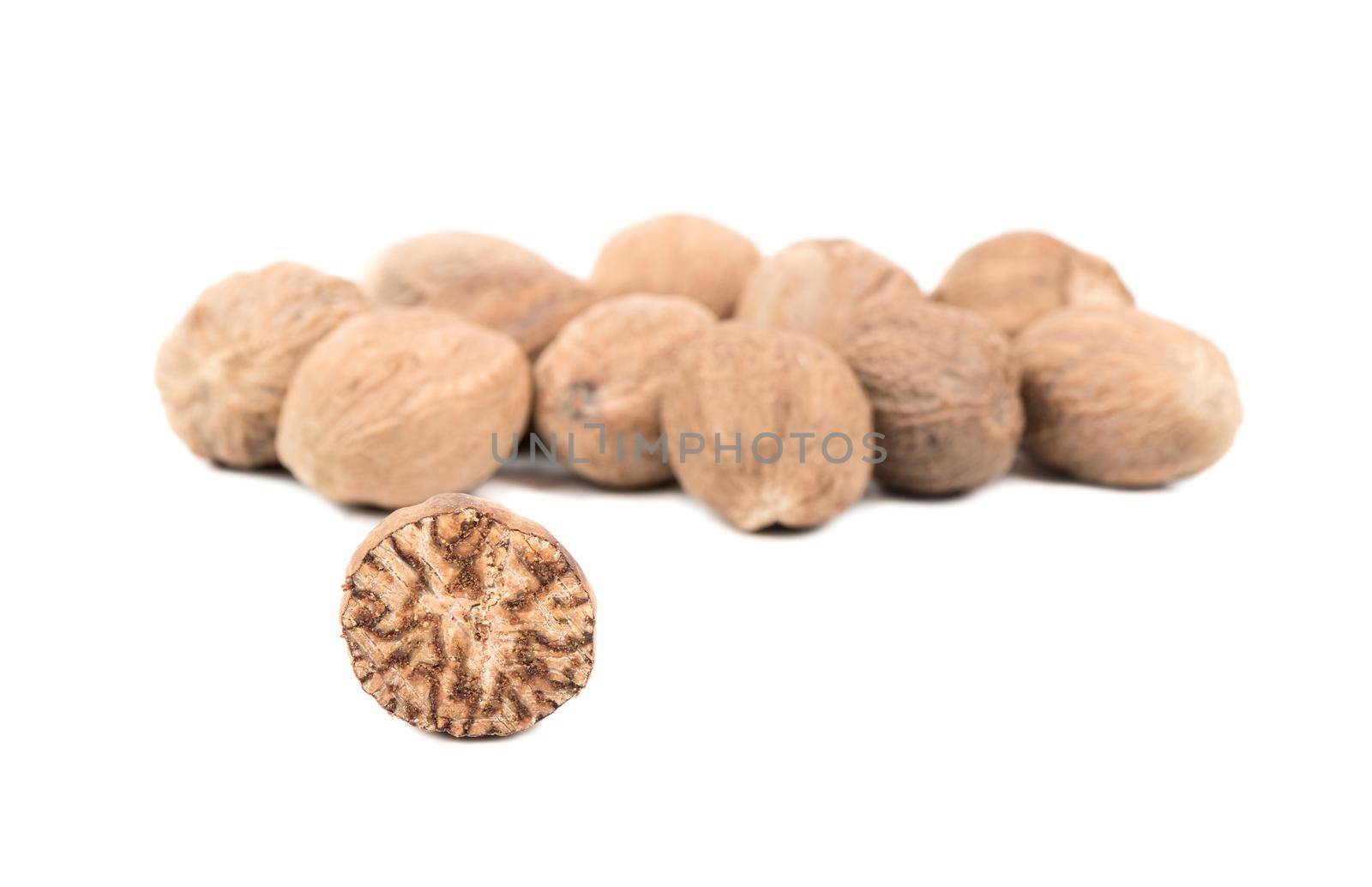 Half of a nutmeg with a bunch of nuts on a white background