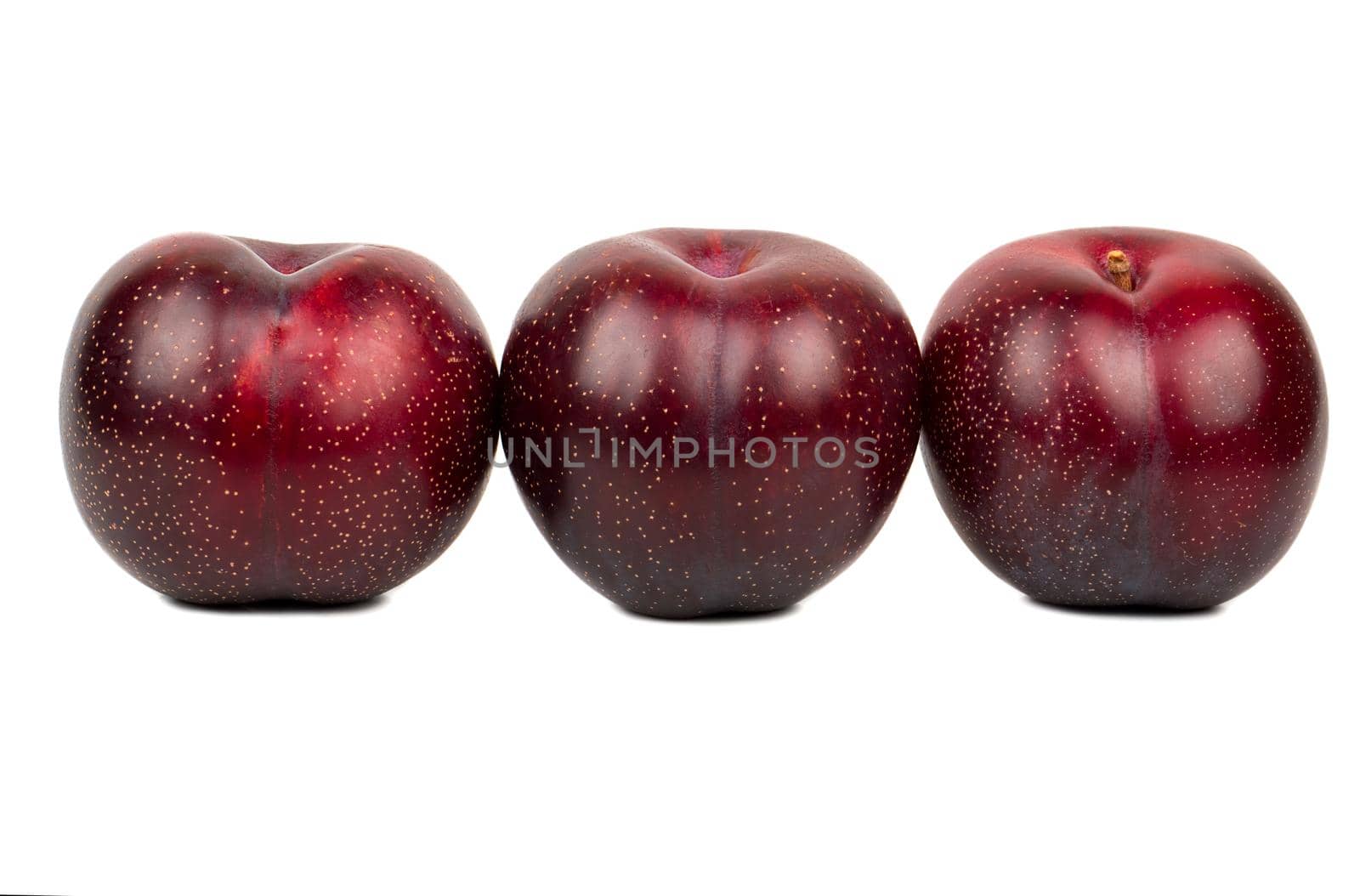 Three ripe big red plums in a row on white background
