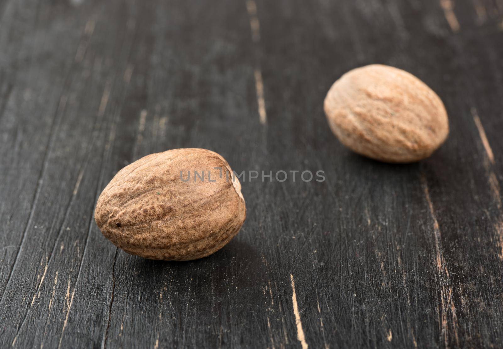 Two dry nutmeg on dark wooden background