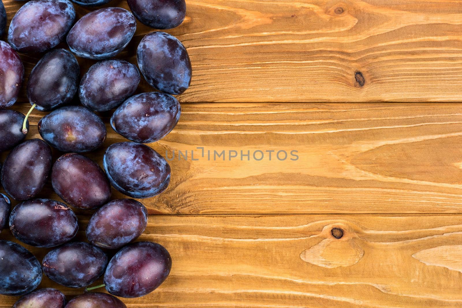 Fresh blue plums on a blank wooden background