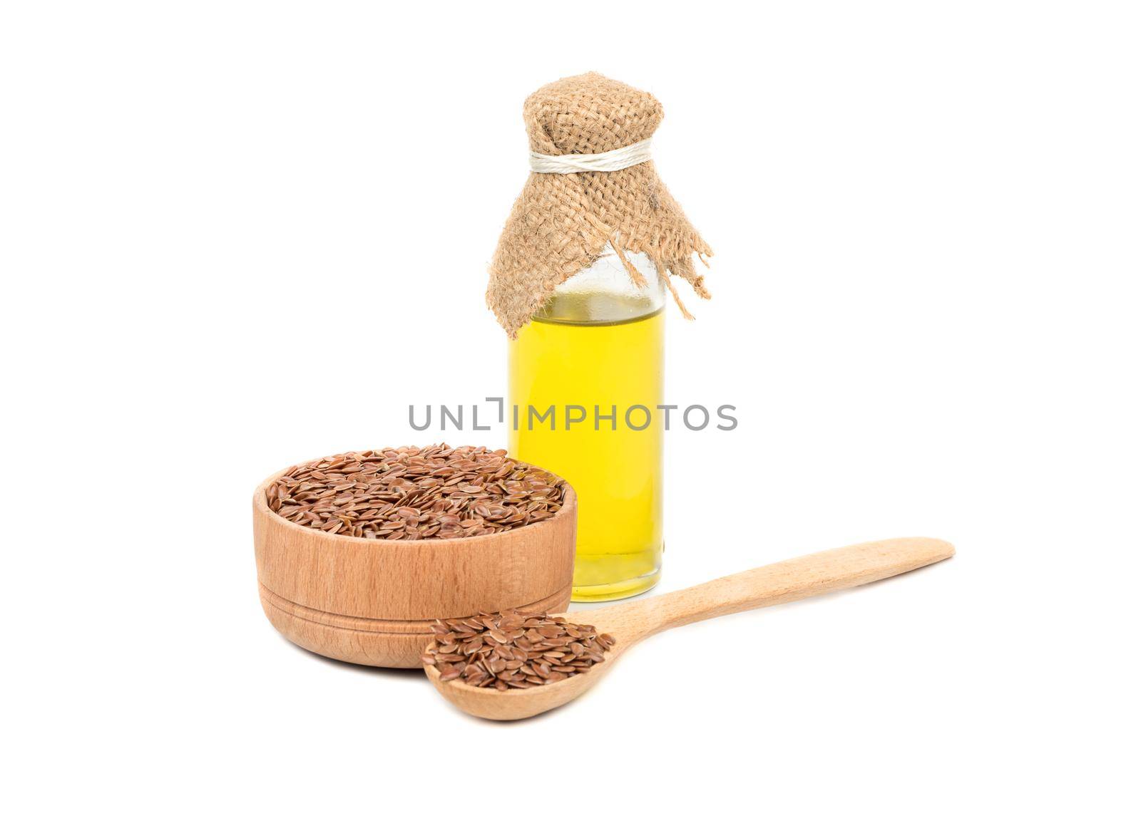 Bowl, spoon with seeds and a bottle of linseed oil on white background