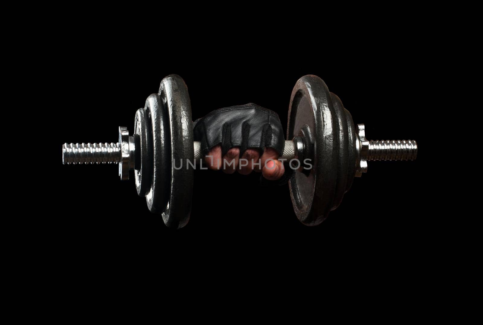 Iron dumbbell in the hand on black background close-up