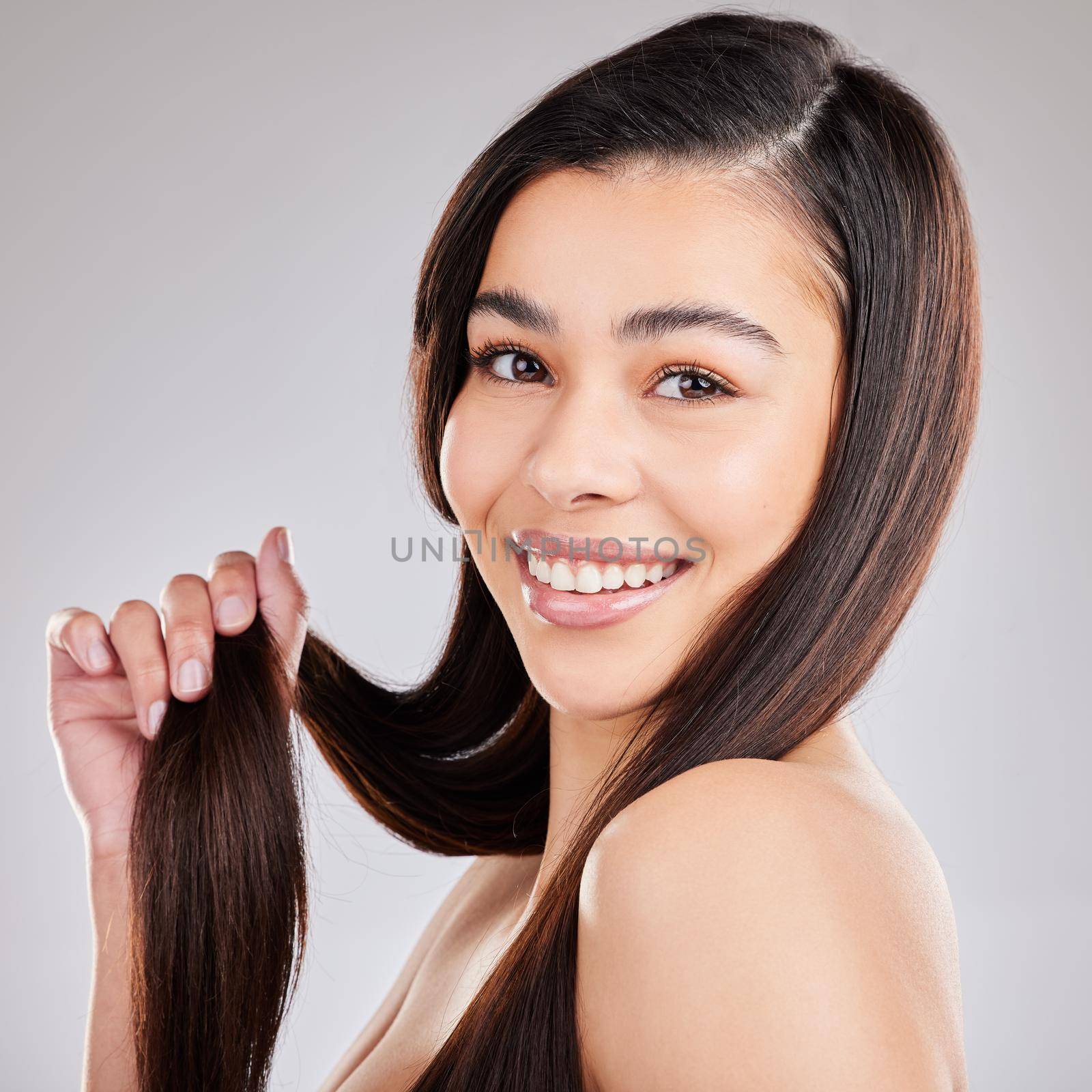 My hair looks and feels healthier. Studio shot of a young woman with beautiful long hair. by YuriArcurs