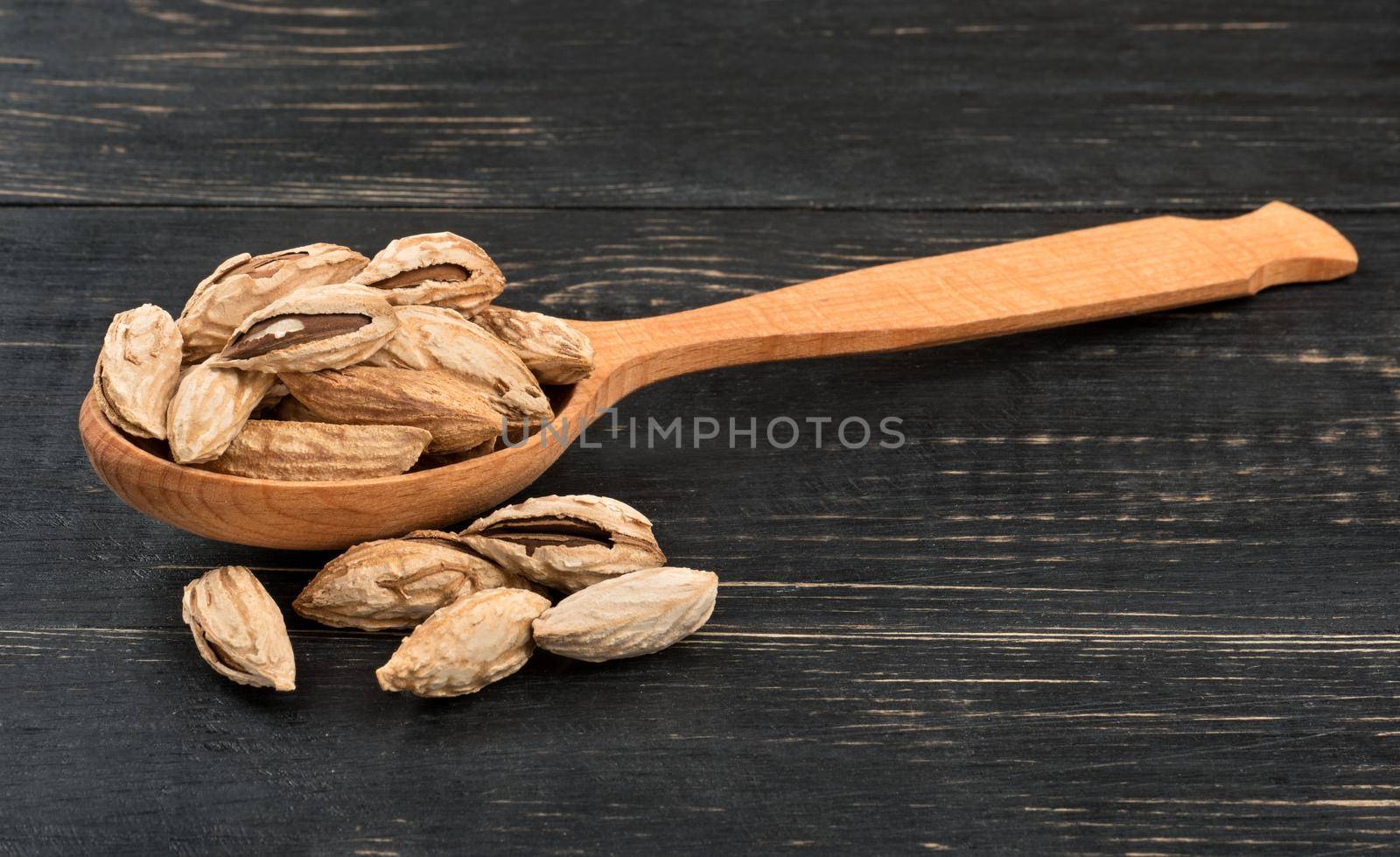 Wild uzbek almonds in a wooden spoon on dark table