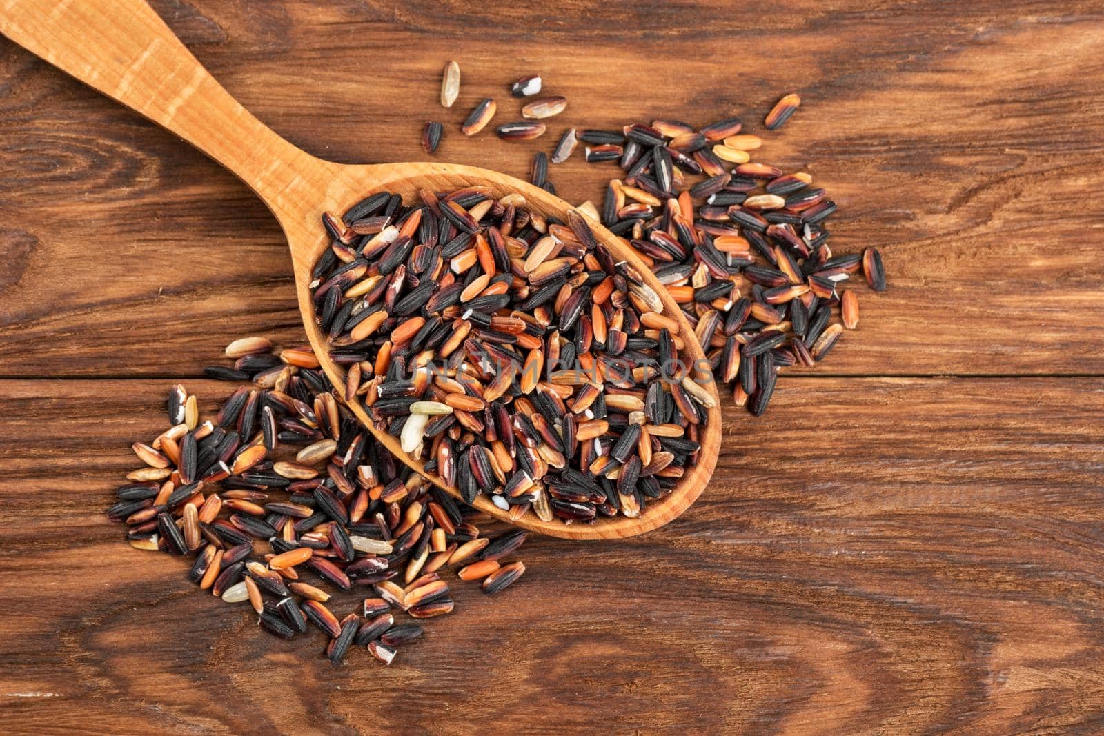 Wooden spoon with raw wild rice on the table close-up