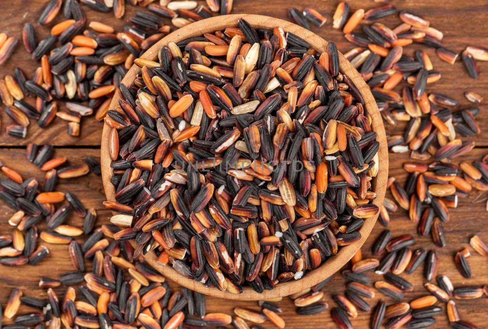 Black rice in a small bowl on a wooden background top view