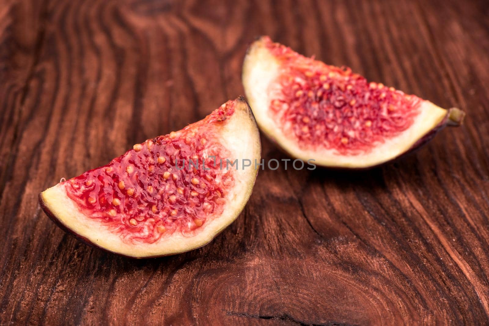 Two slices of fresh figs on a wooden background