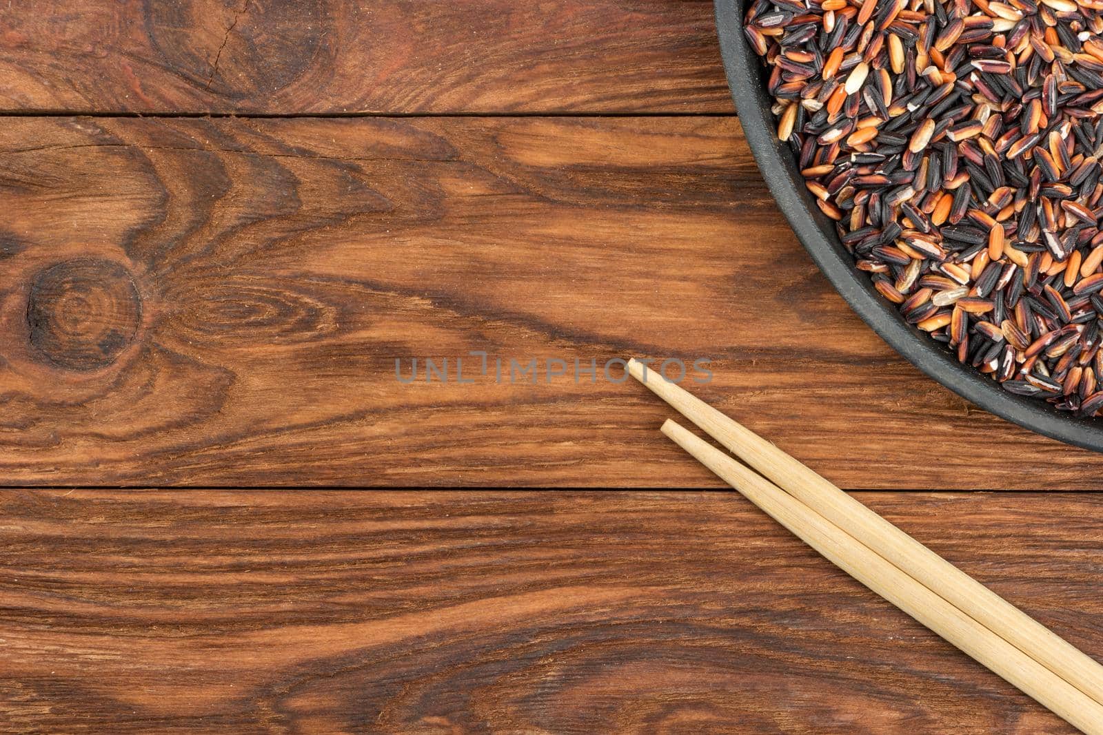 Wild rice in a pan with chopsticks on the table, top view