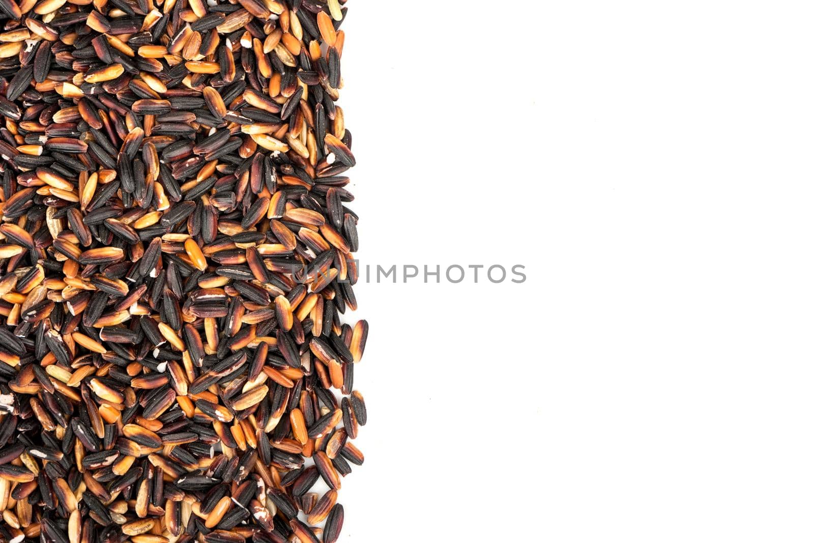 Scattered raw black rice on white background, top view