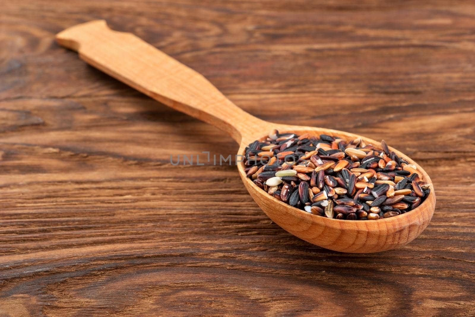 Raw wild rice in a spoon on the table close-up