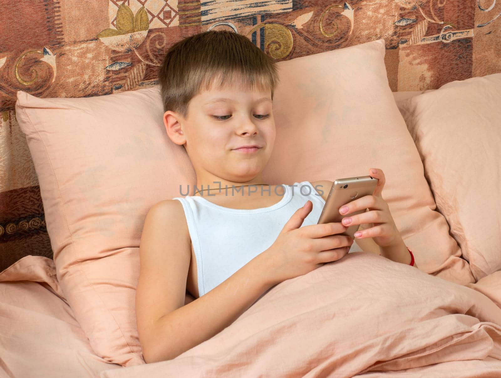 Boy with phone in bed by andregric