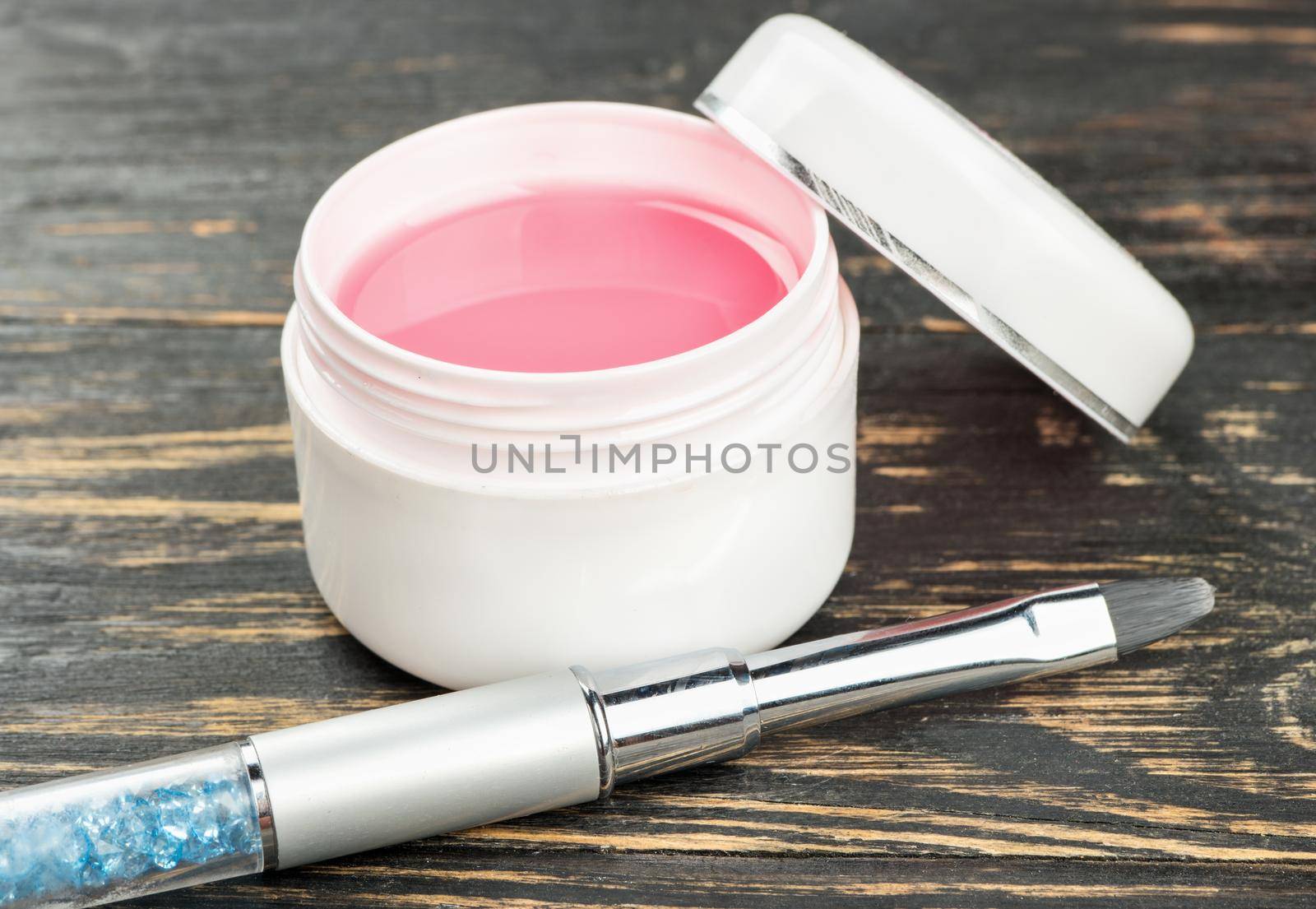 Brush for nail extension with pink gel on the table closeup