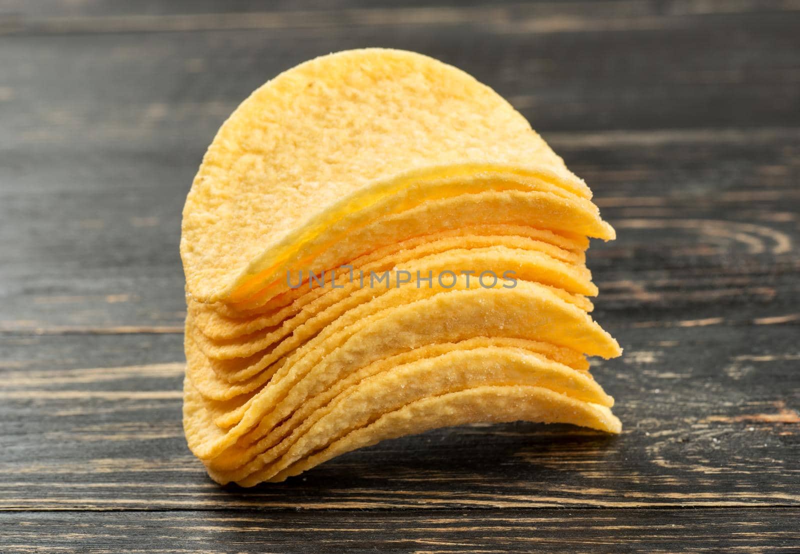 Stack of potato chips on wooden background closeup