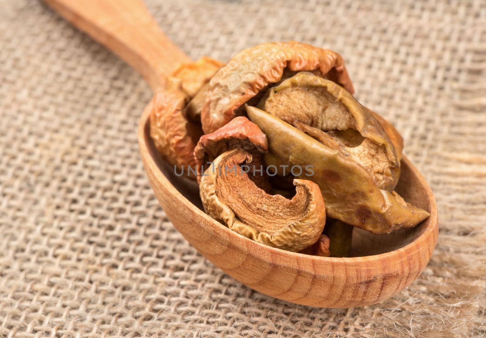 Wooden spoon filled with dry apple slices closeup on burlap