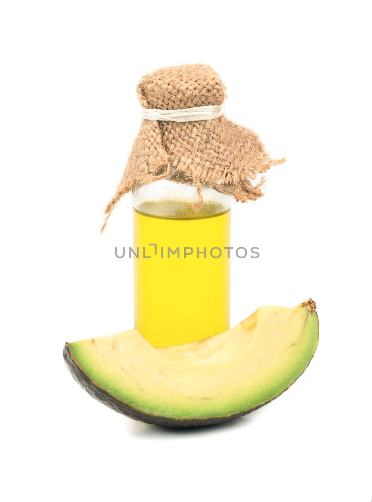 Avocado oil in a bottle with a slice on white background