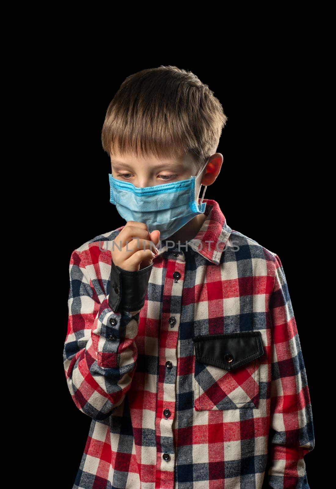 Sick boy in medical mask coughs on black background