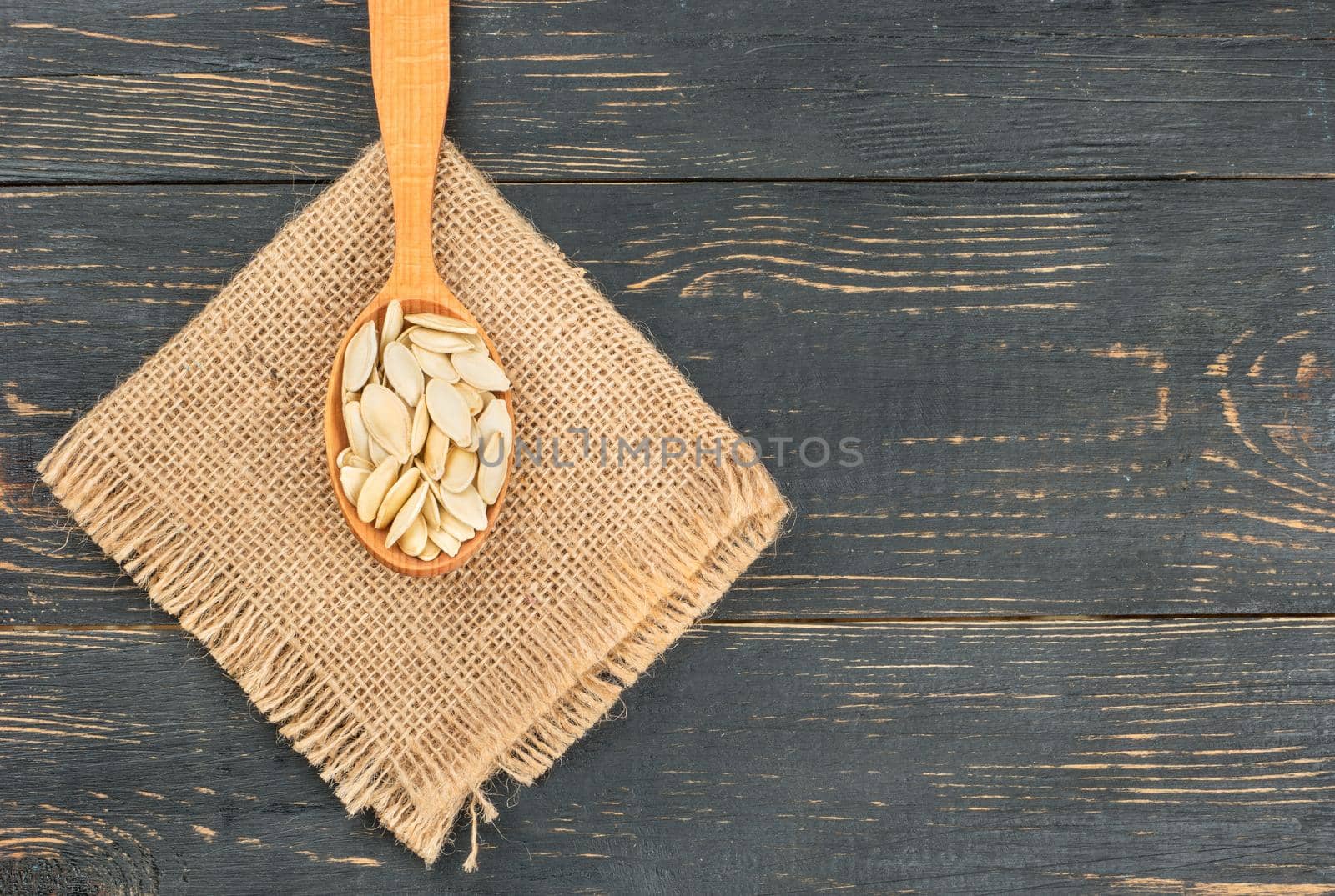 Pumpkin seeds in shell on burlap on wooden background