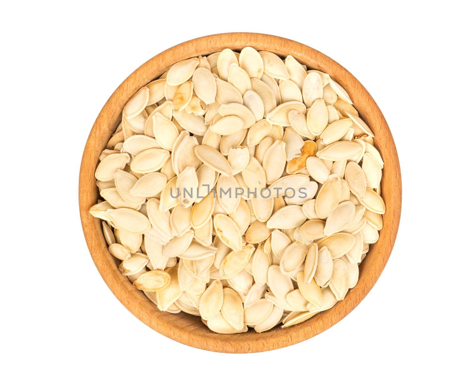 Roasted pumpkin seeds in a wooden bowl on a white background, top view