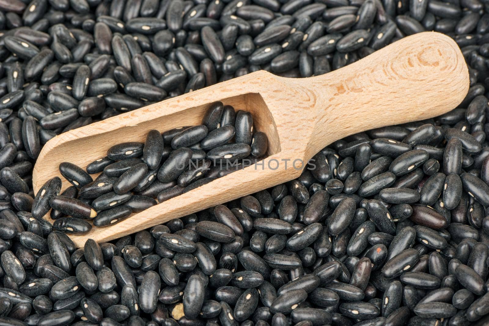 Bunch of raw black beans with a wooden scoop closeup