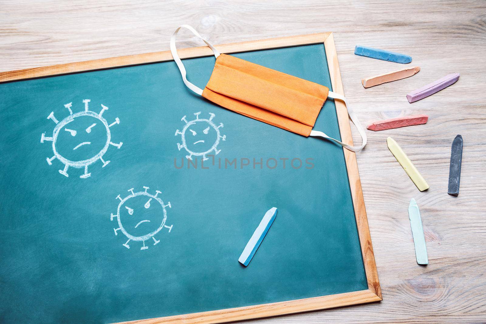 virus on a blackboard next to a protective mask