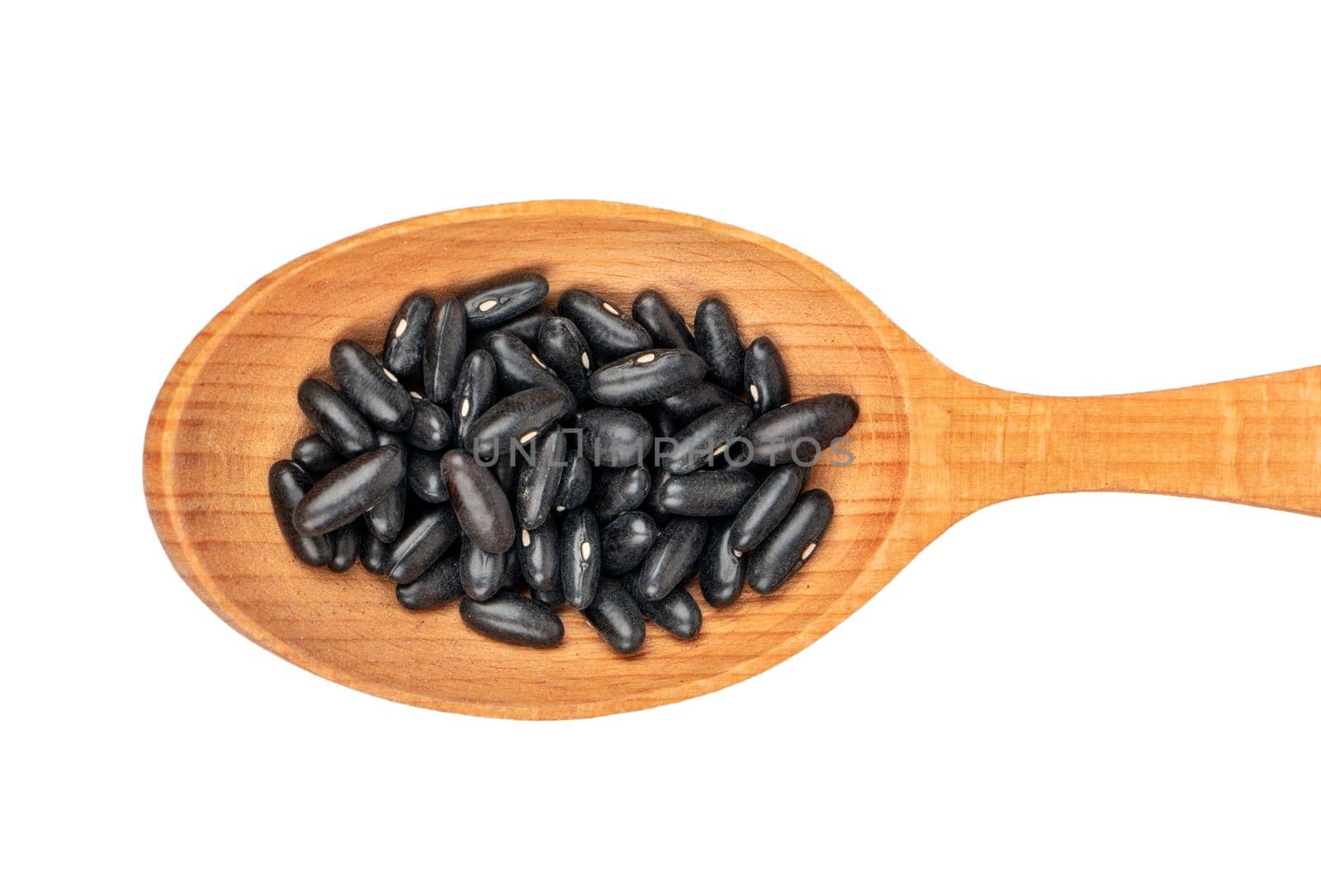 Large wooden spoon with black beans on white background, top view