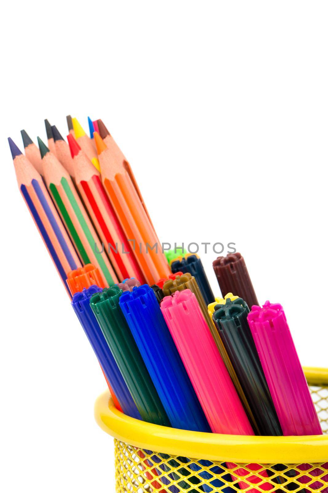 Colored pencils and markers in a basket closeup on white background