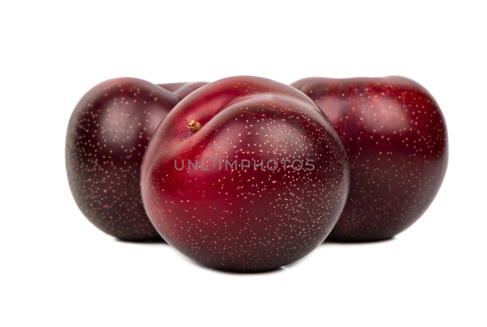 Three ripe large red plums on white background