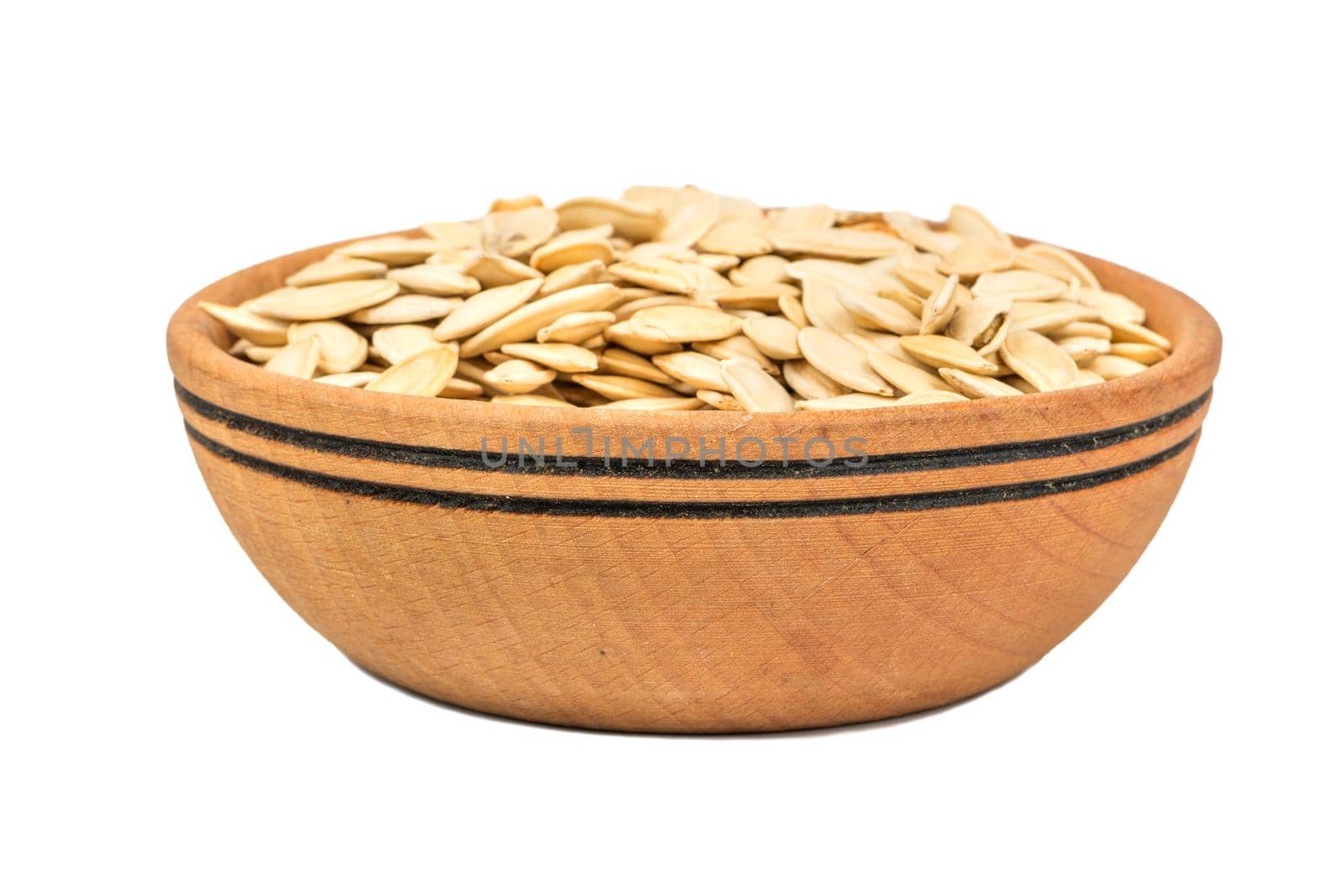 Roasted pumpkin seeds in a wooden bowl on a white background