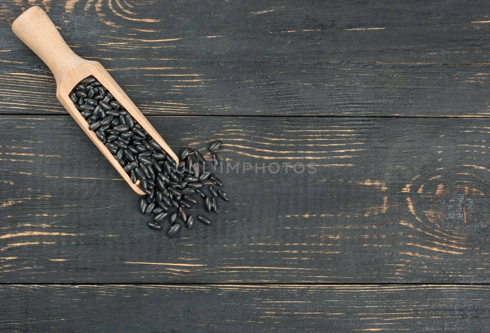 Scoop of black beans on an empty wooden background