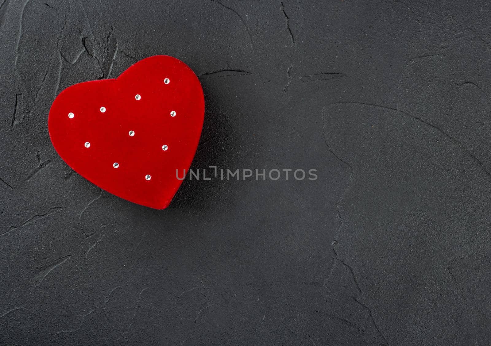 Red box for rings in the shape of a heart on a concrete background, top view