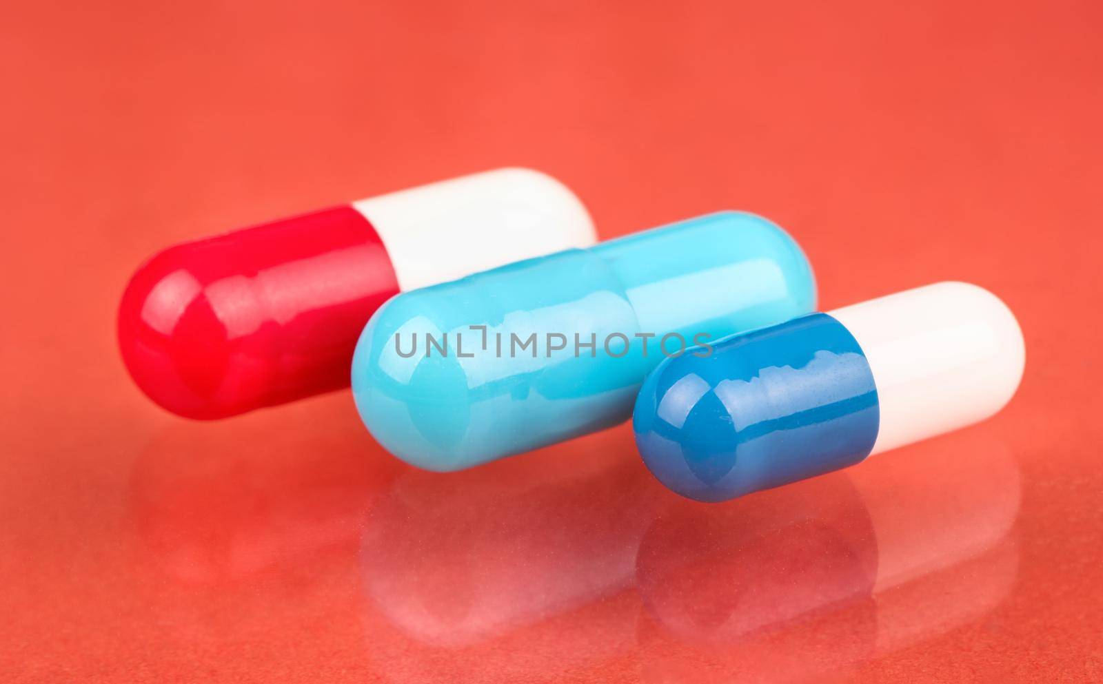 Three various color and shape capsules on a peachy background