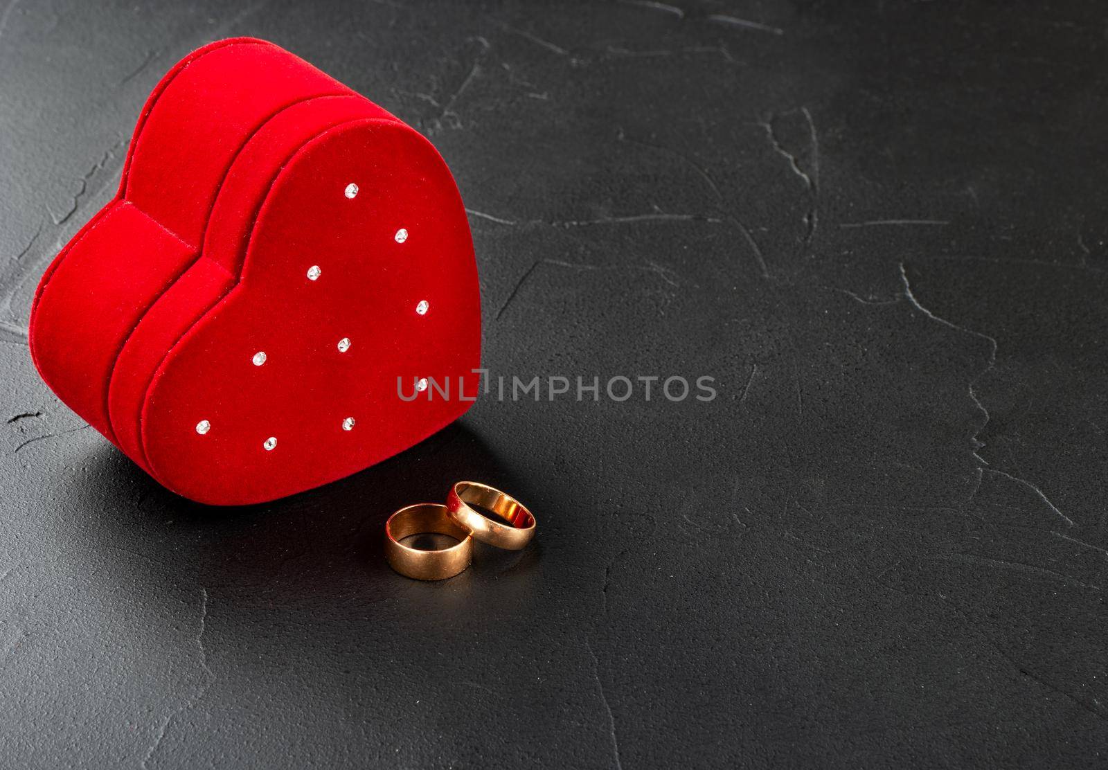 Two wedding rings with red box on dark background
