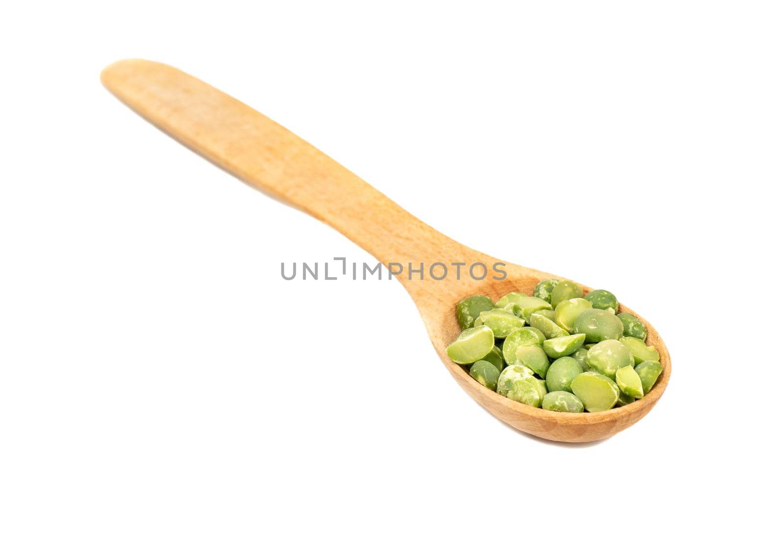 Small wooden spoon with dry green peas on white background closeup