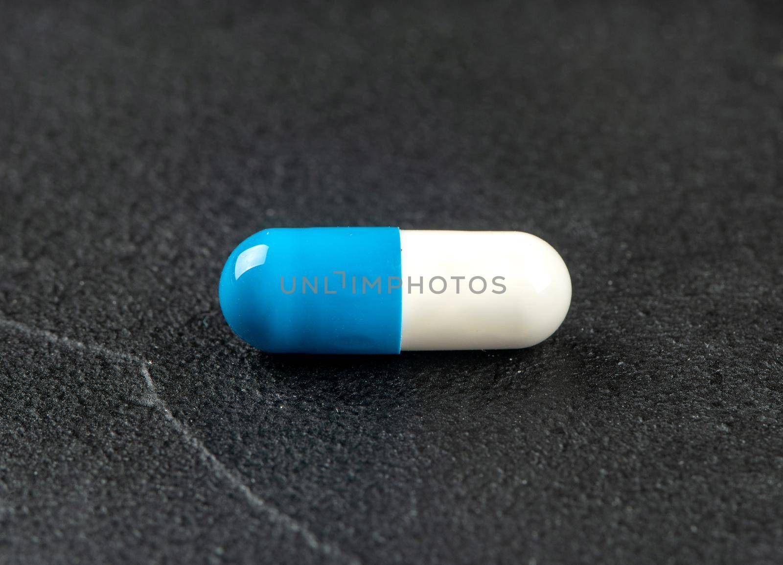 White blue capsule on dark concrete background